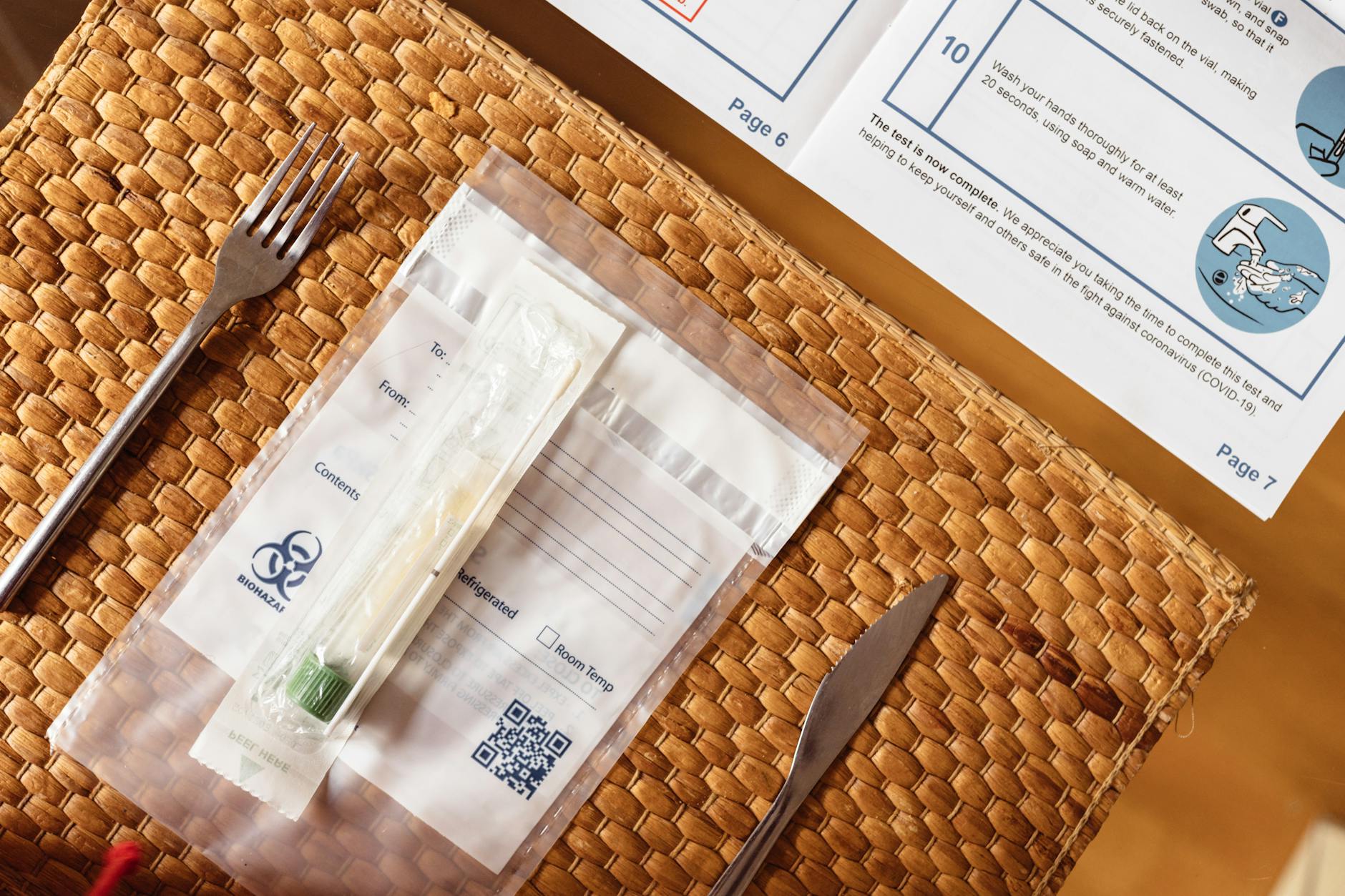 Zestaw testu COVID-19 na plecionym podkładce obok sztućców