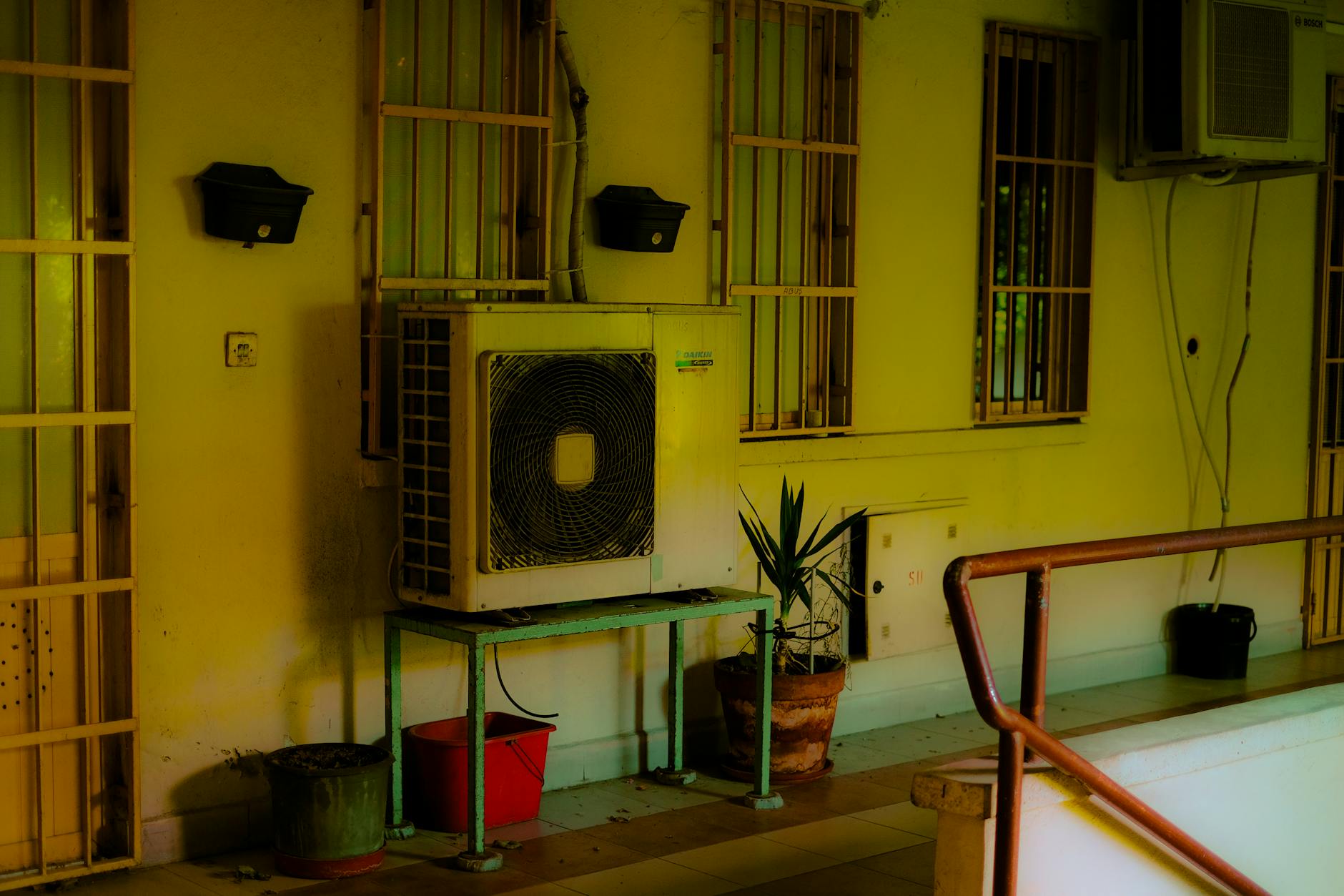 Jednostka klimatyzacji na balkonie z donicami w bloku miejskim