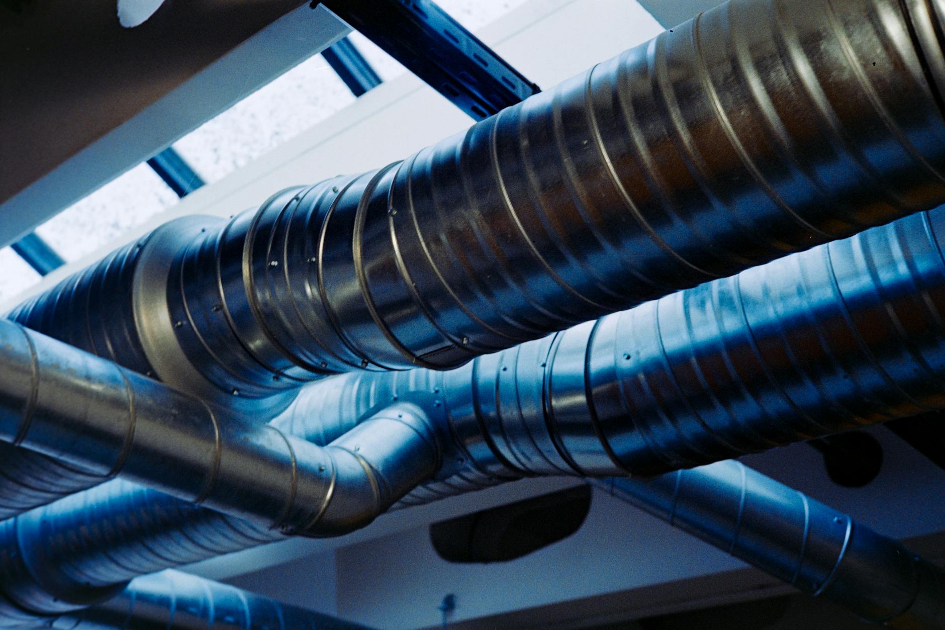 Metalowy system wentylacyjny z kanałami w nowoczesnej hali industrialnej