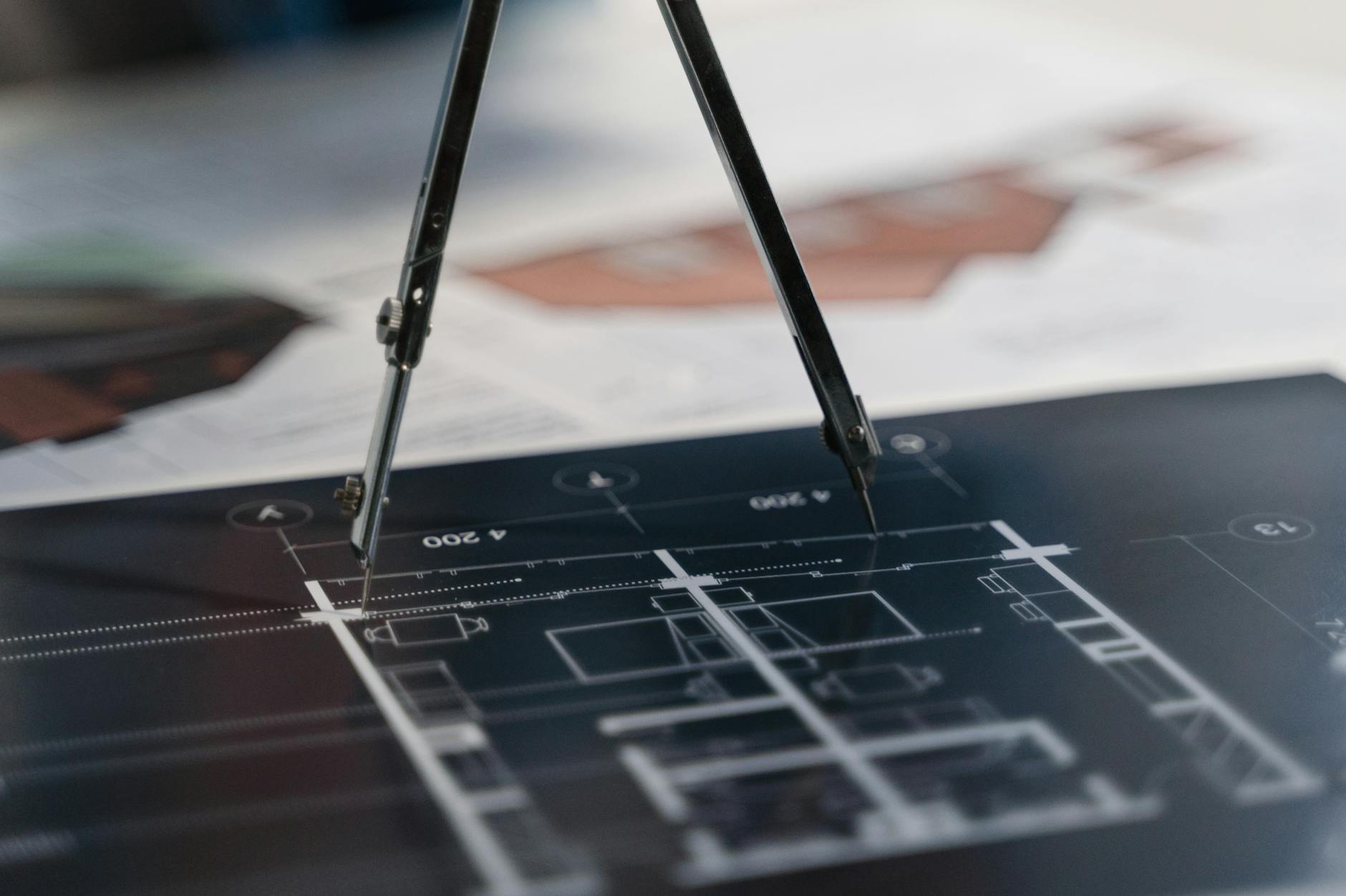Cyrkiel leżący na papierowych planach architektonicznych